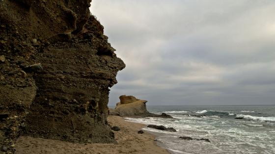 Rocky cliff on a beach with cloudy sky