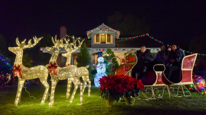 Family poses for photo in sleigh on Bennett Ranch House Lawn at Heritage Hill Historical Park. 